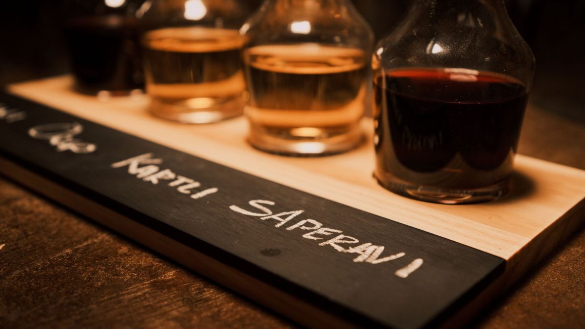 Ein Glas Rotwein, das eingegossen wird und verschiedene Stücke Käse
