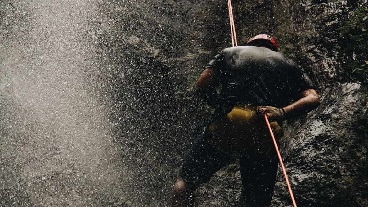 EIn Mann, der an einem Seil in einem Wasserfall hängt